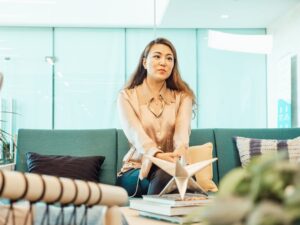 Professional woman sitting on a sofa in a contemporary office setting, conveying calm and focus.