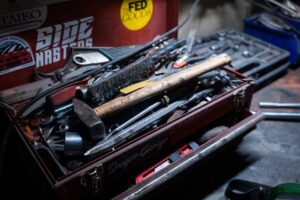 Detailed close-up of a cluttered toolbox filled with various hand tools in a workshop.