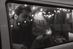 A joyful couple enjoying a winter night inside a vehicle, with twinkling lights creating a festive ambiance.