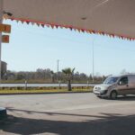 A van parked at a roadside gas station under a clear blue sky.