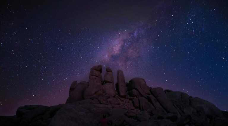 Beautiful view of the Milky Way over a rocky outcrop under a starry night sky, showcasing celestial wonders.