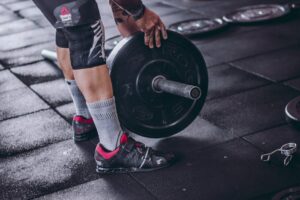A focused man lifting a heavy barbell during weightlifting exercise in a gym.