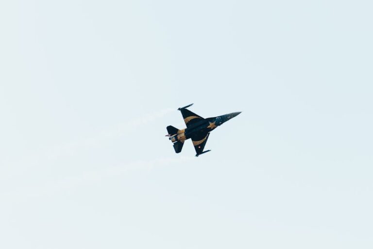 A jet fighter executes an aerobatic maneuver against a clear sky, demonstrating speed and agility.