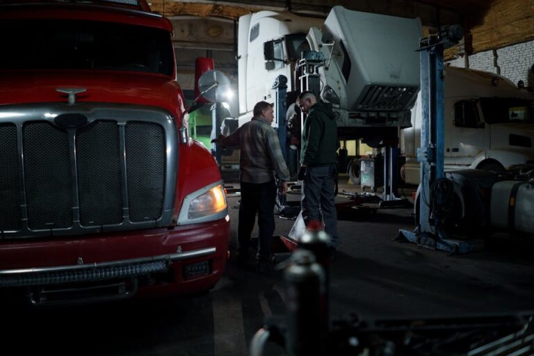 Mechanics performing truck maintenance and repair in an indoor garage setting.