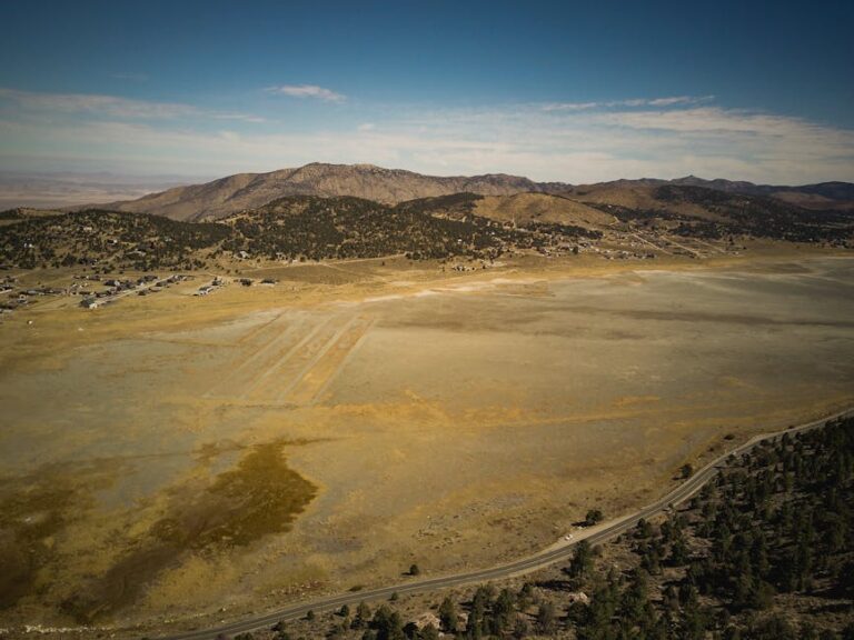 Aerial shot showcasing expansive arid terrain with distant mountains under a clear blue sky.