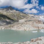 Captivating landscape of the Rhône Glacier and serene turquoise lake in Swiss Alps.