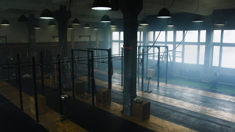 Spacious industrial-style gym interior with no people, showcasing equipment and natural light.