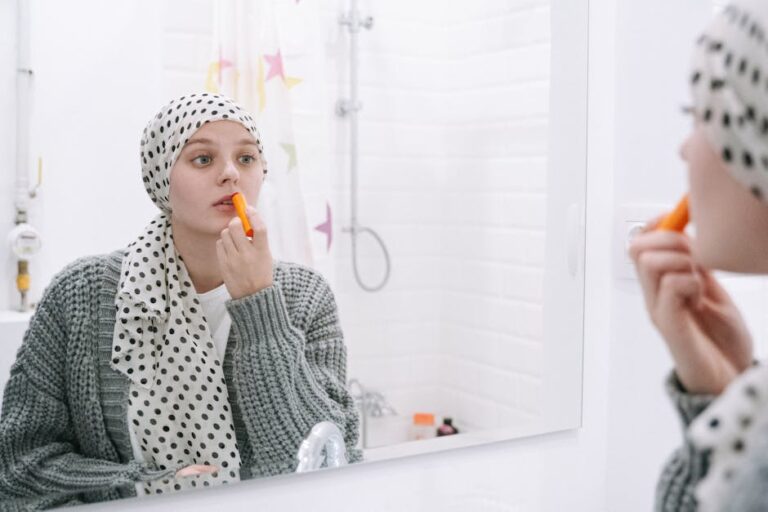 A woman in a headscarf applies lip balm, symbolizing strength and cancer awareness.