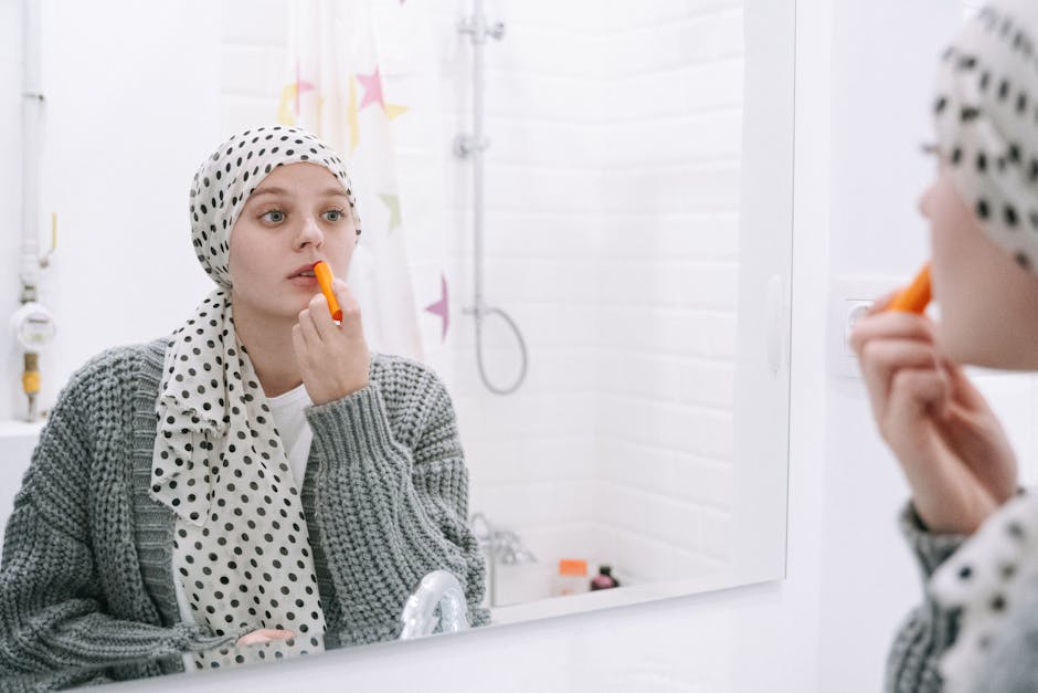 A woman in a headscarf applies lip balm, symbolizing strength and cancer awareness.