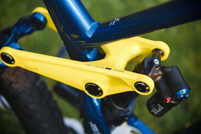 Detailed view of a mountain bike's yellow shock absorber arm and suspension system.