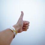 A hand giving a thumbs up gesture symbolizes approval and positivity.