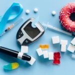 Flat lay of diabetes essentials and sugary food on blue background symbolizing health awareness.