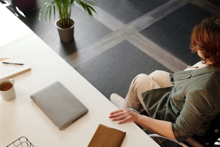A woman working at a desk with a laptop and coffee in a modern office space.