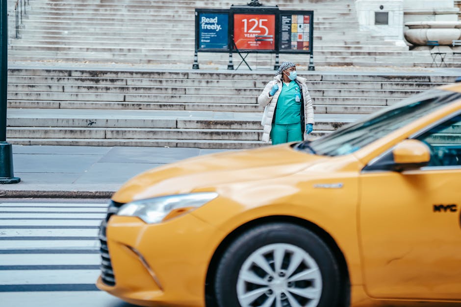 African American female doctor in uniform looking away from sidewalk against taxi cab on roadway in town