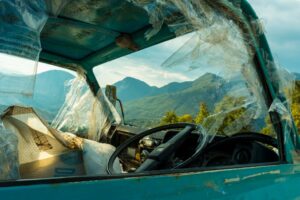 Old rusty truck with broken windows in front of mountain landscape, symbolizing decay.