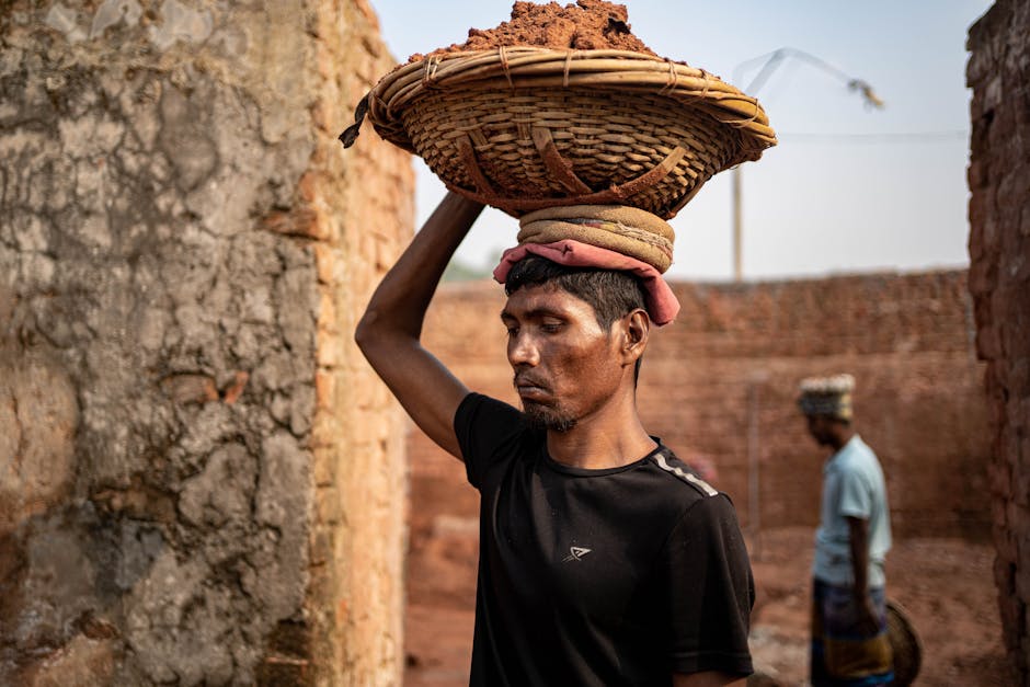 A laborer carries bricks at a brick field in Dhaka Division, Bangladesh, symbolizing hard work and perseverance.