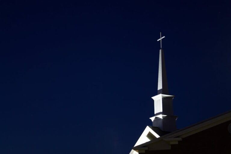 Illuminated church steeple with cross at night. Perfect for religious and architectural themes.